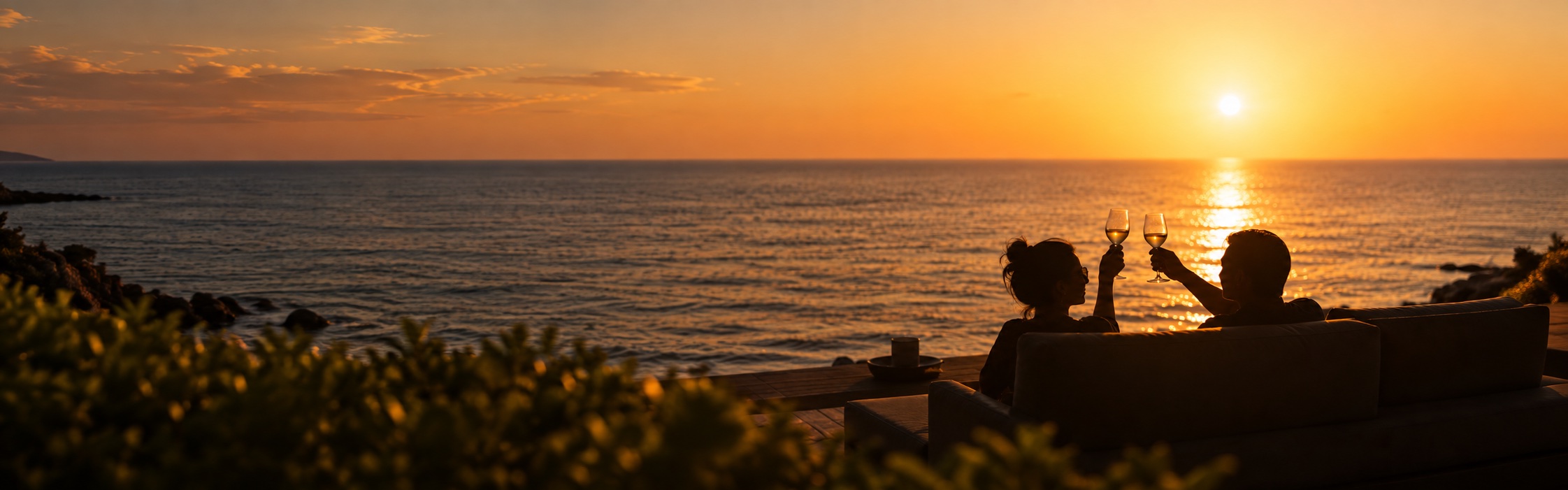 A couple toasting beside the water at sunset